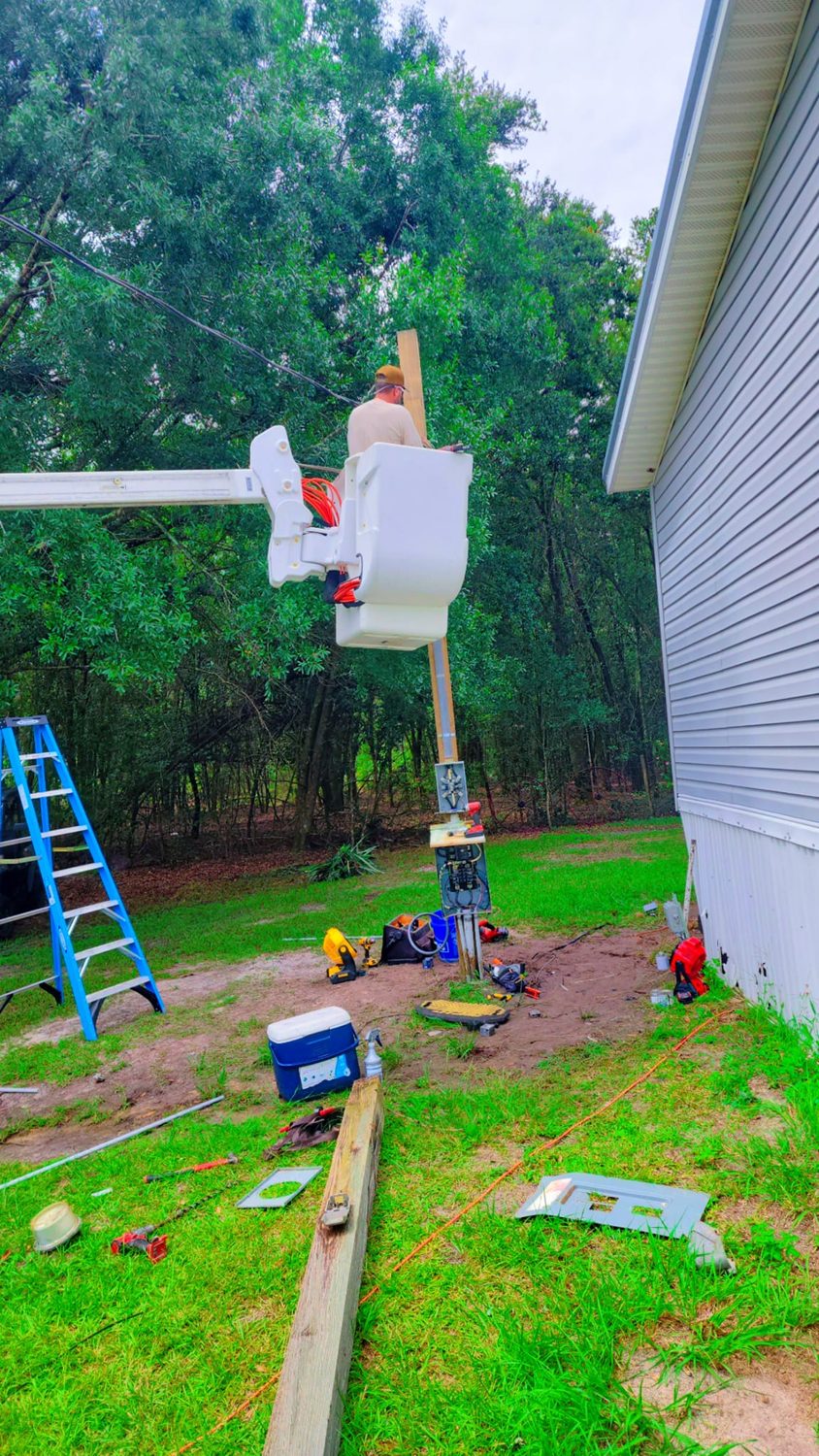 Barnes Electric technician replacing a mobile-home service mast / pole-riser from a bucket truck